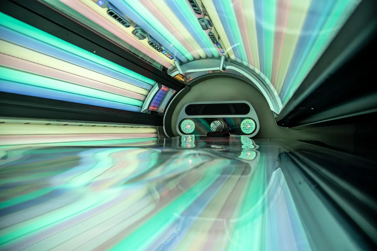 Interior of a commercial tanning sunbed with illuminated UV lamps